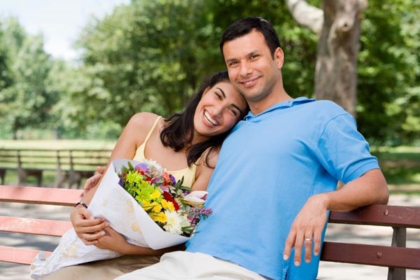 Couple poses Holding on Park Bench